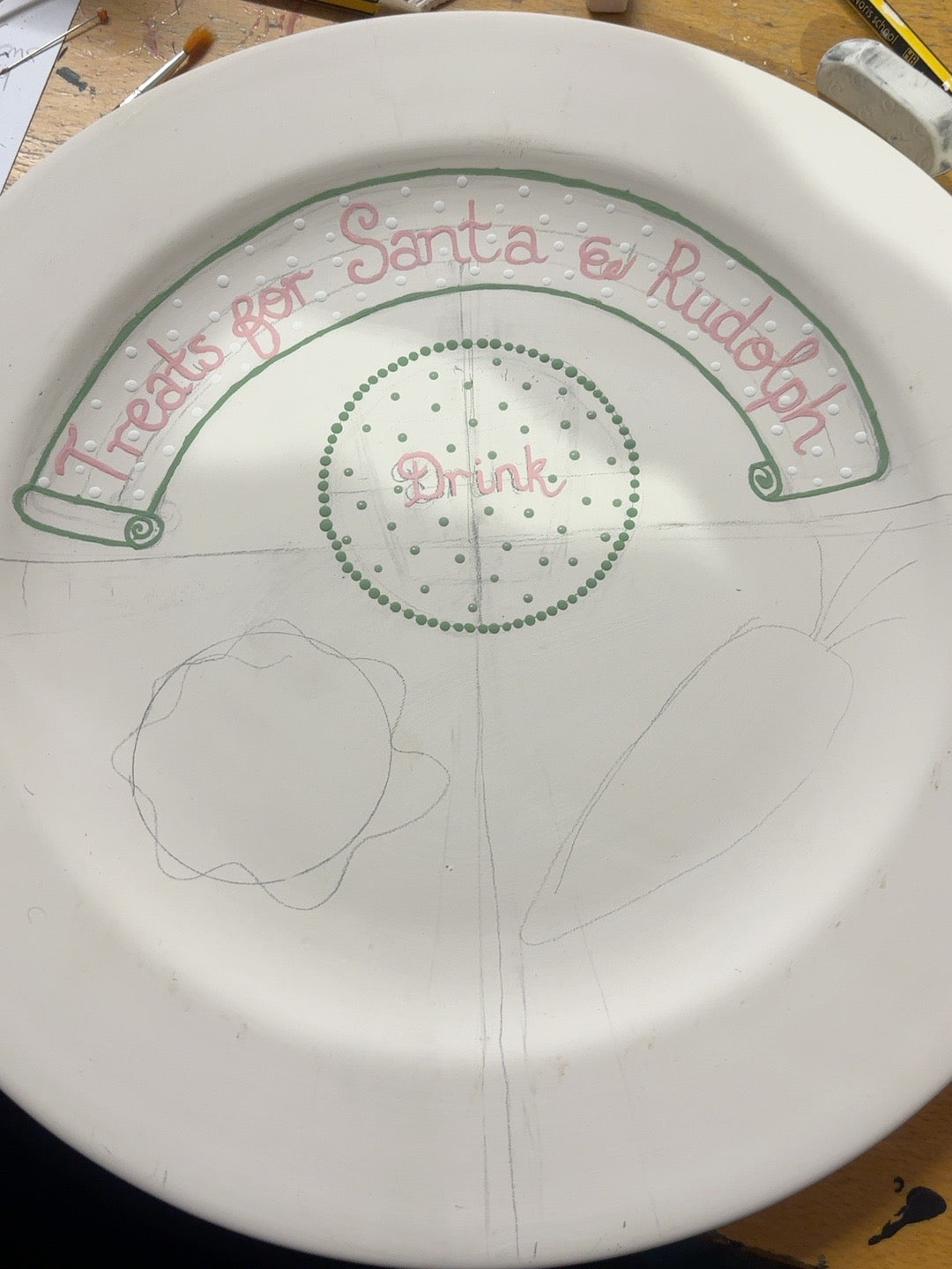 Santa and Rudolph ceramic plate in progress with green dotted drink circle and sketched cookie