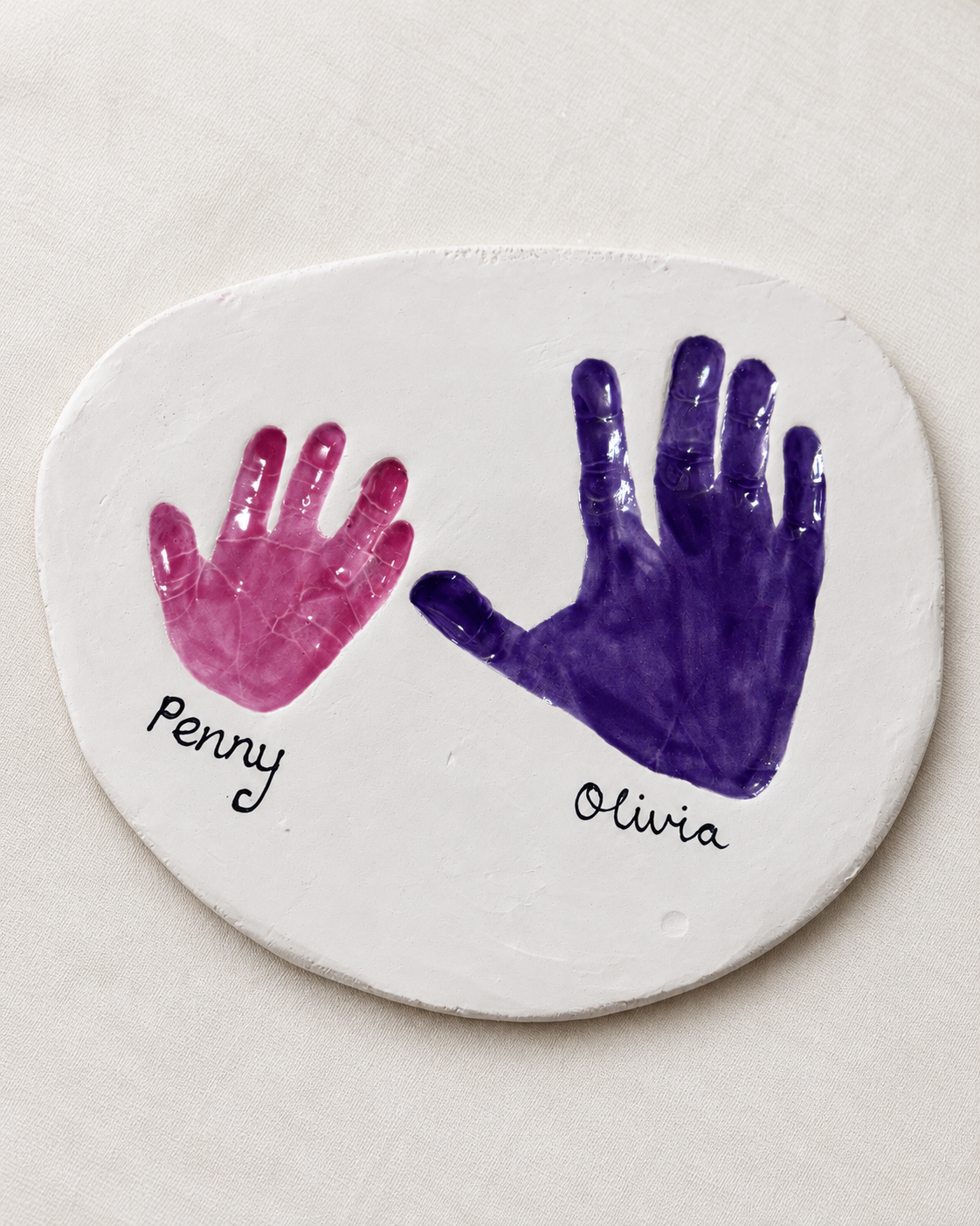 Personalised ceramic keepsake plaque with pink and purple clay handprints named Penny and Olivia