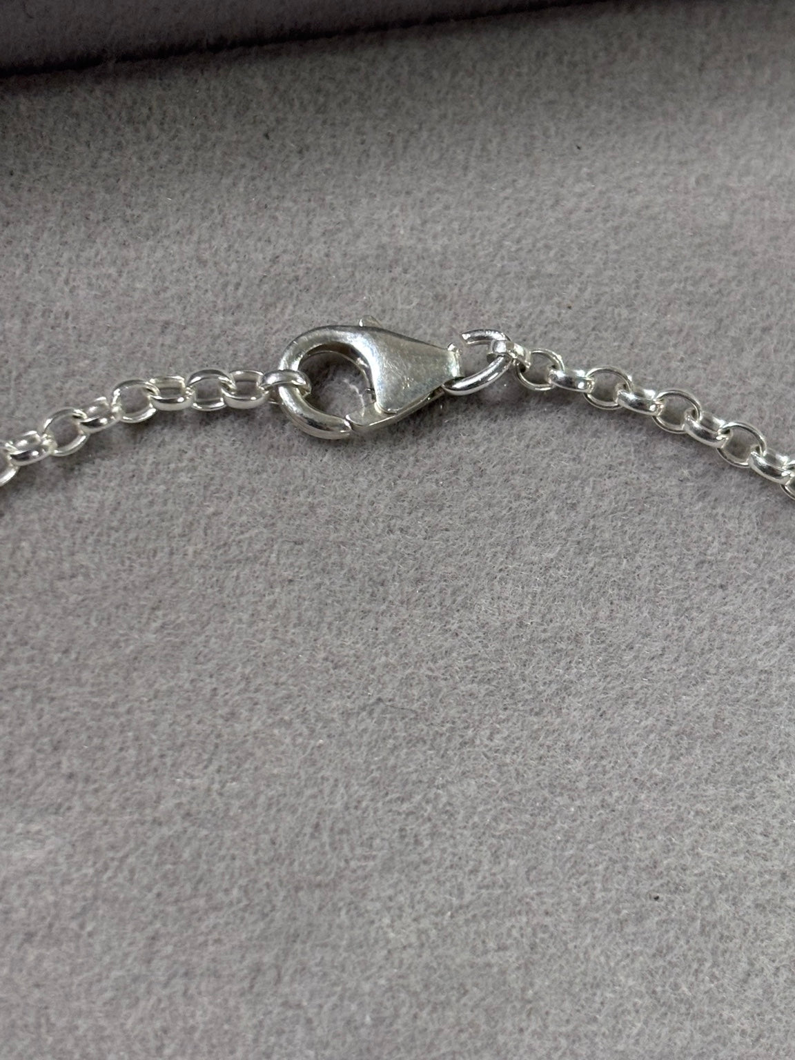 Close-up of sterling silver lobster clasp and oval belcher chain on personalised bracelet