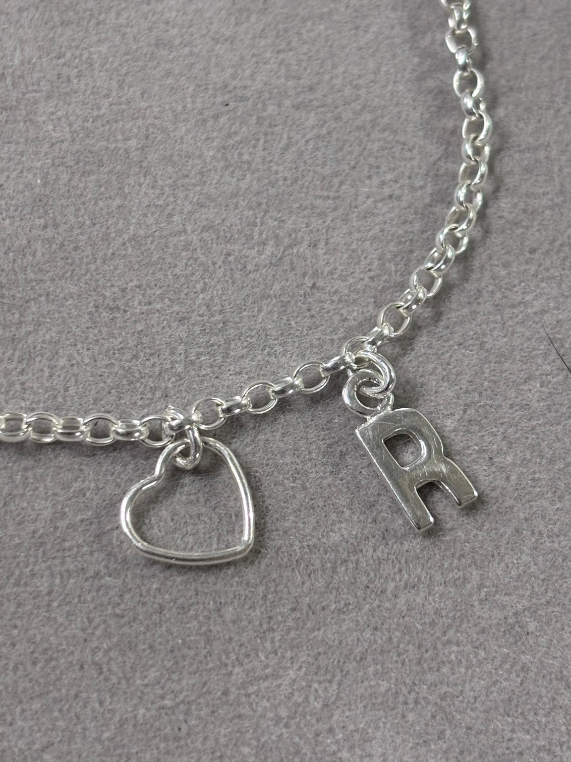 Close-up of sterling silver open heart and R initial charms on handmade bracelet